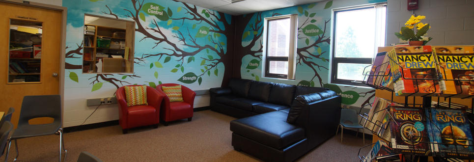Couch and two chairs in a corner of the Learning Commons,image of tree on the wall with key words, self control
